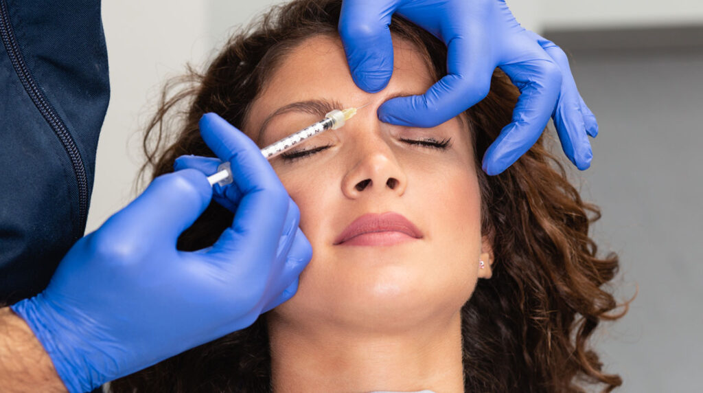 Gros plan extrême sur une main gantée de chirurgien tenant un instrument chirurgical fin avec des fils de suture ultra-fins visibles, arrière-plan totalement flouté